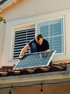 pexels-photo-9875409-9875409 A worker installing a solar panel on a residential rooftop under bright sunlight.